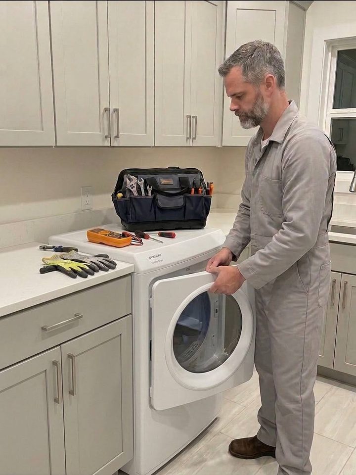 Technician removing the door of a white dryer in a laundry room